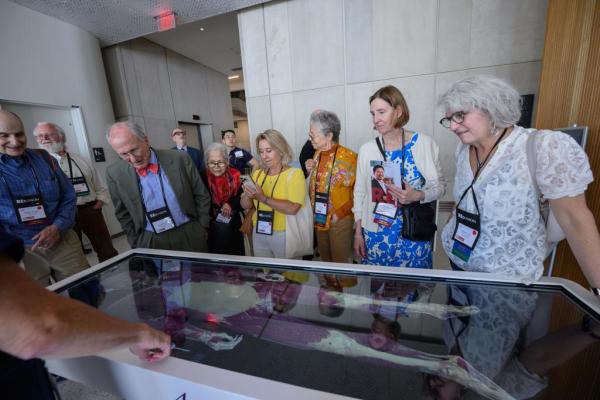 Alumni watching a demonstration of the Anatomage Table while touring Countway Library.