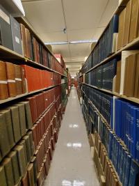 A long row bookshelves on both sides of a narrow corridor in Countway Library.