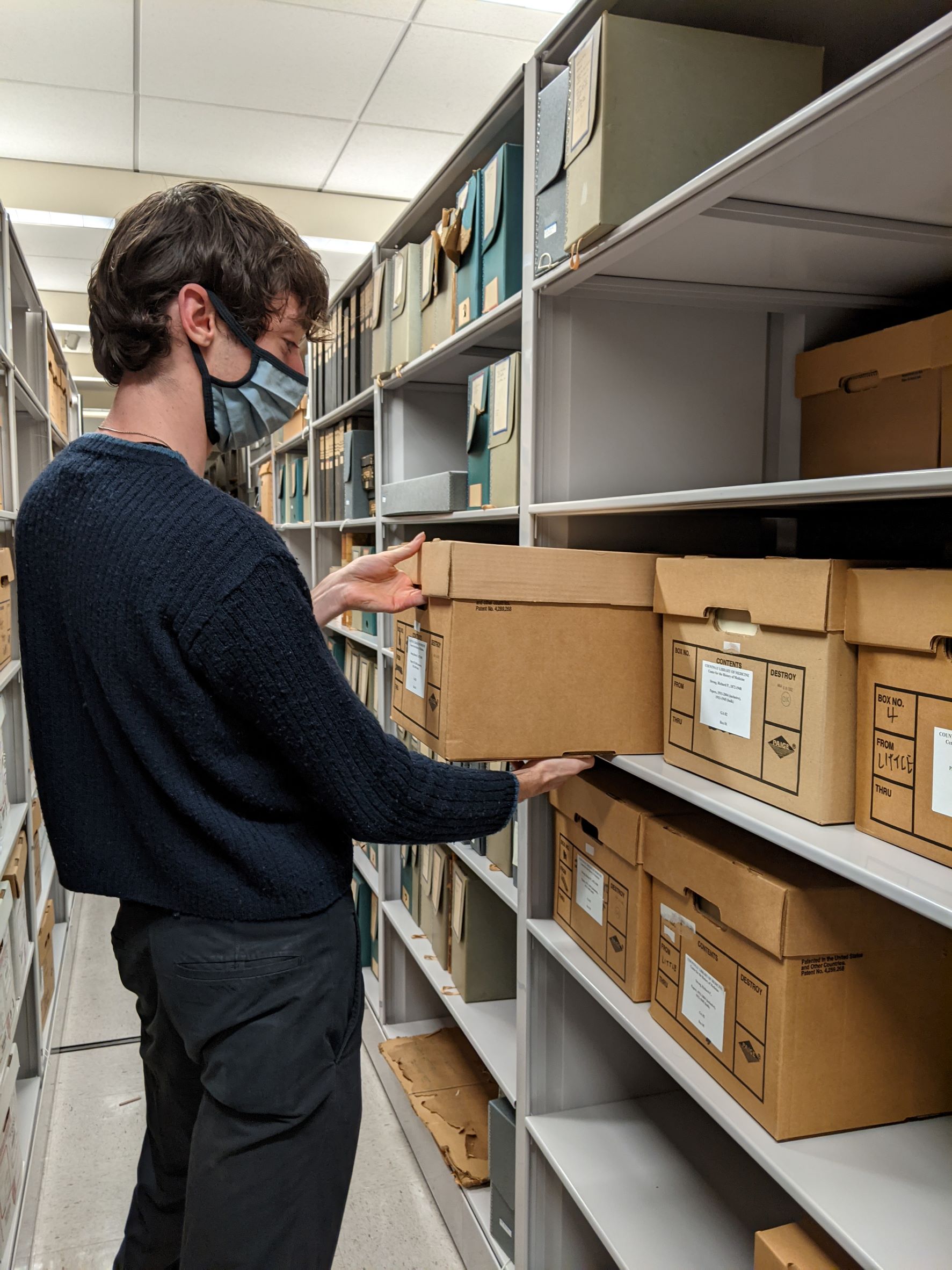 Marco places a records center carton on the shelf in the stacks